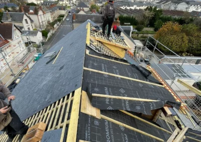 Couvreurs rénovant un toit en ardoise au-dessus d’une ville