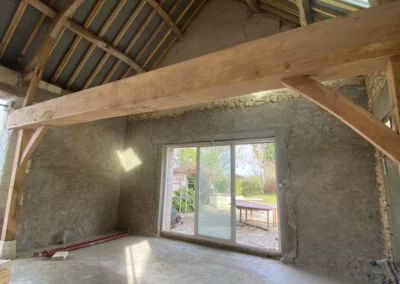 Intérieur en rénovation avec charpente apparente et baie vitrée