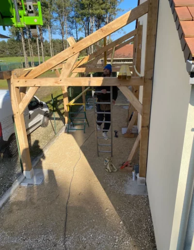 Charpentier montant une ossature bois contre une maison
