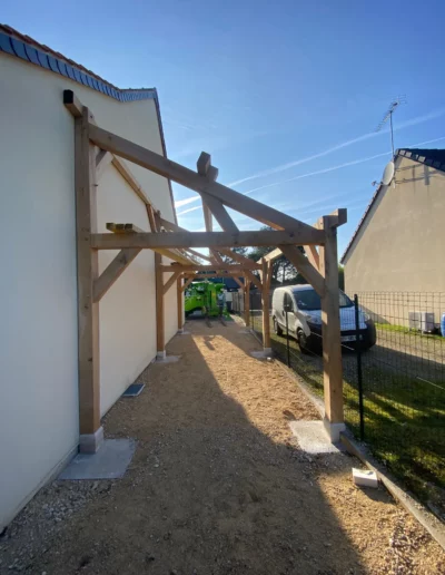 Ossature de préau en bois entre deux maisons