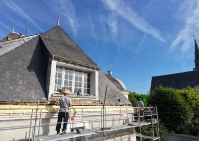 Couvreurs rénovant une toiture en ardoise sur échafaudage