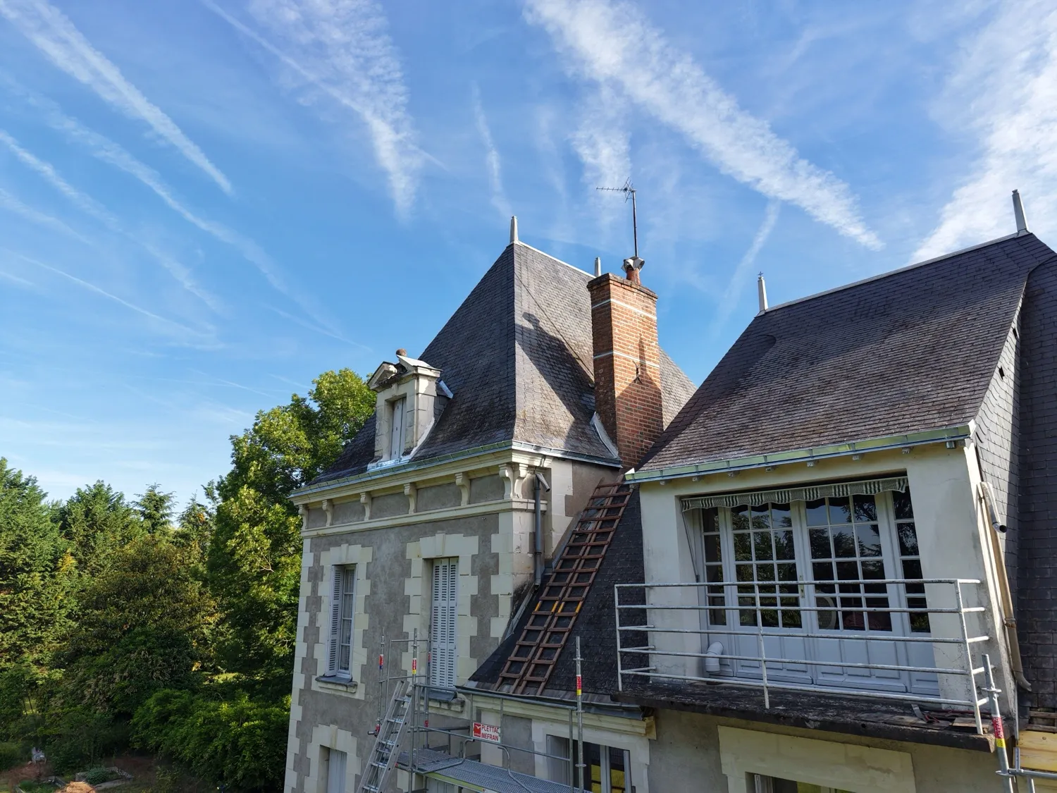 Toiture d’une maison ancienne en travaux sous ciel bleu