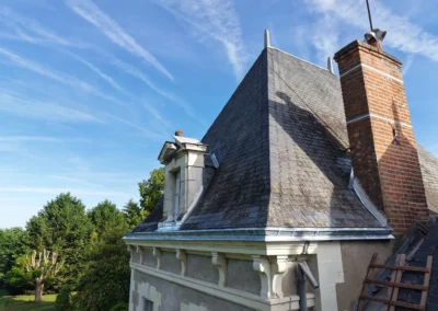 Toiture en ardoise avec cheminée sous ciel bleu