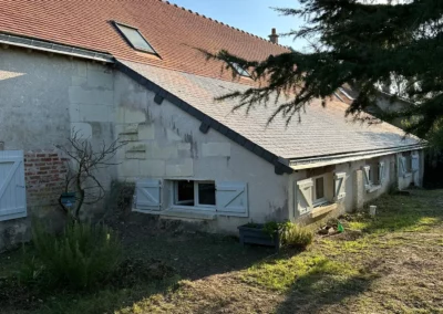 Maison ancienne au toit de tuiles et volets blancs
