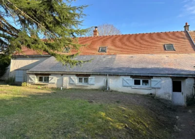 Maison traditionnelle aux volets blancs sous un grand arbre