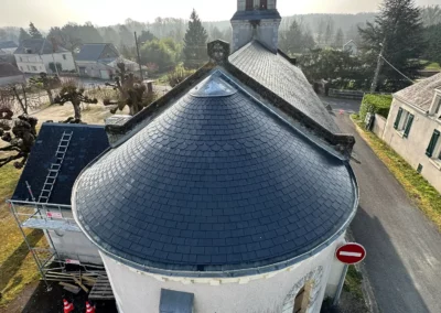 Toit d’une chapelle devant un clocher villageois