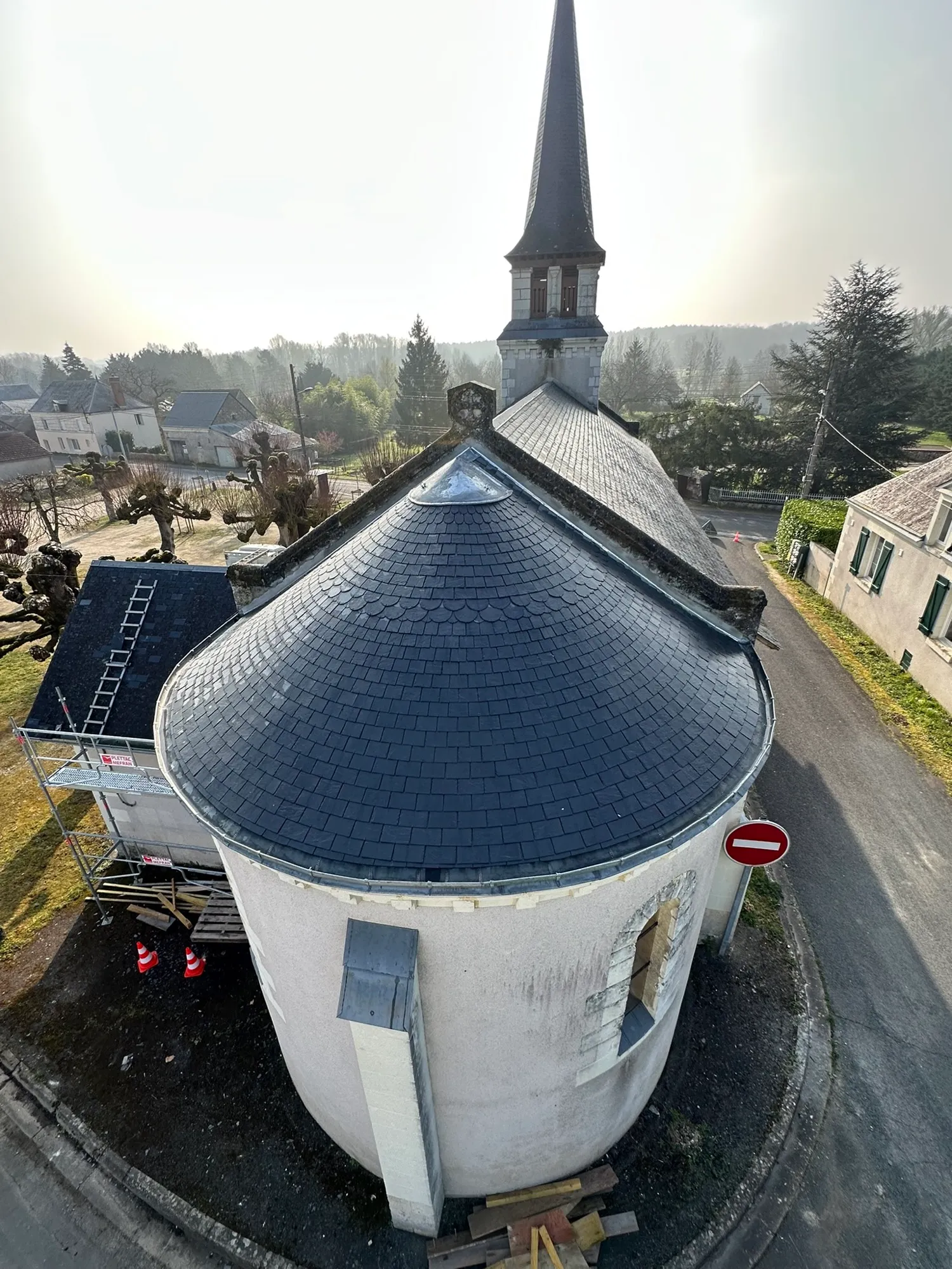 Toit d’une chapelle devant un clocher villageois
