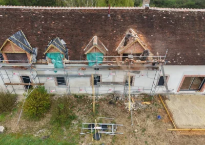 Couvreur rénovant la toiture d’une maison ancienne sur échafaudage