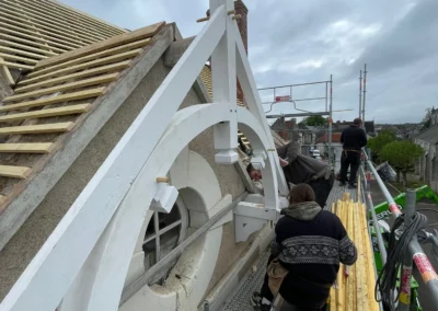 Artisans restaurent une charpente décorative sur échafaudage