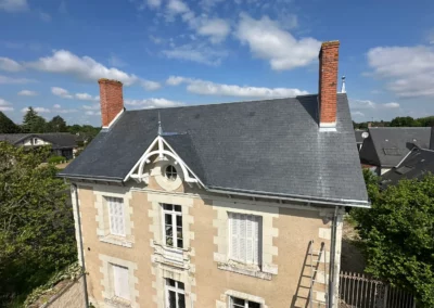 Maison ancienne à toit d’ardoise sous ciel bleu