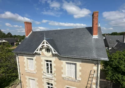Toiture en ardoise d’une maison ancienne avec deux cheminées