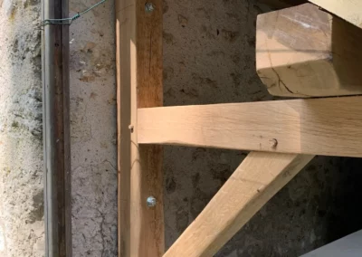 Charpente en bois fixée contre un mur ancien