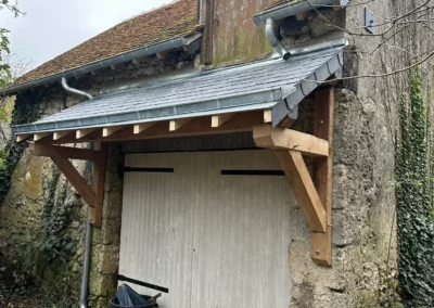 Auvent neuf sur porte de grange en pierre
