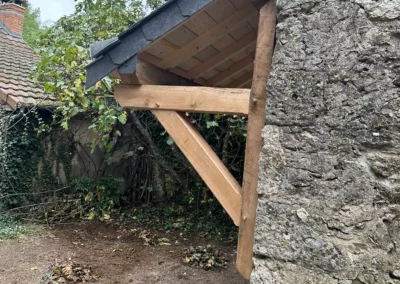 Auvent en bois contre mur en pierre
