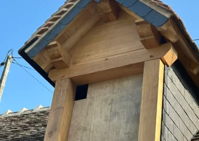 Lucarne en bois sous toit d’ardoises