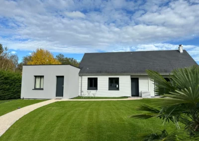 Maison moderne blanche avec jardin verdoyant et ciel nuageux