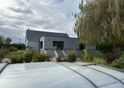 Maison contemporaine grise entourée d’un jardin arboré
