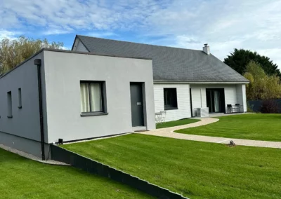 Maison contemporaine avec jardin verdoyant sous ciel nuageux
