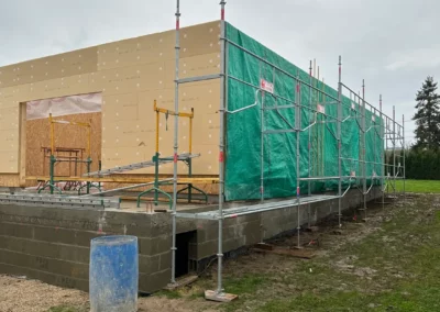 Maison en construction entourée d’échafaudages et bâches vertes