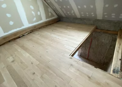 Combles en rénovation avec parquet, placo et fenêtre de toit