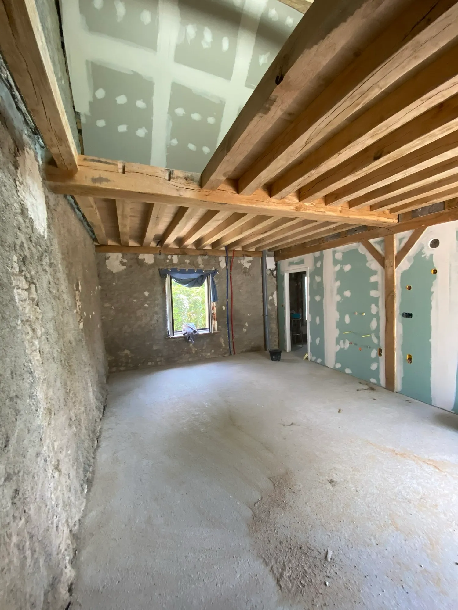 Pièce en rénovation avec poutres apparentes et cloisons en plaques