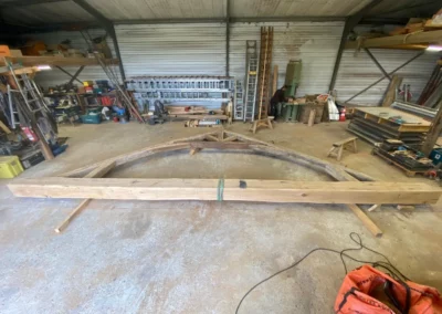 Charpentier assemblant une grande structure courbe en bois