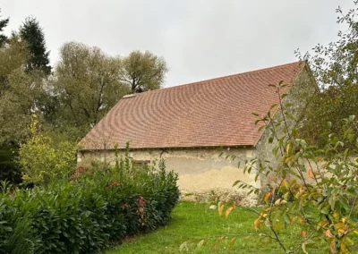 Grange ancienne au toit de tuiles entourée de verdure